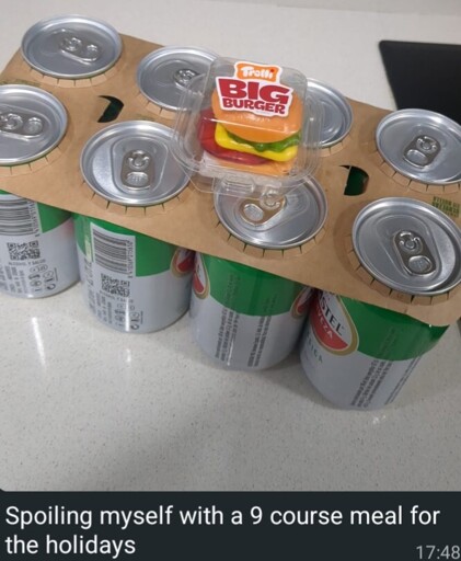 An eight pack of cheap beer cans and a tiny gummy candy burger. The caption reads "Spoiling myself with a 9 course meal for the holidays"