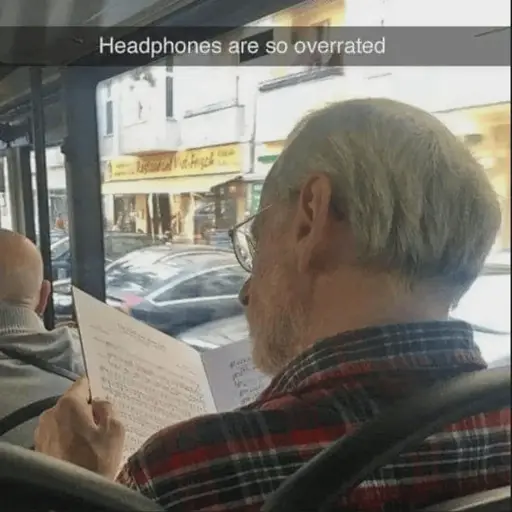 A man reading sheet music, riding the bus